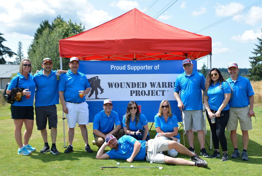 Group of ABC Supply Interior employees in front of Wounded Warrior Project banner